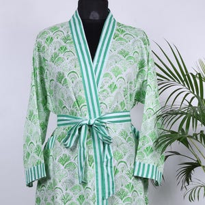 May include: A long, light green robe with a white fan-shaped pattern. The robe has green and white striped trim along the edges and a matching belt. The robe is displayed on a mannequin.