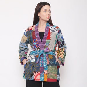 Könnte beinhalten: Eine bunte Patchworkjacke mit einem Bindegürtel. Die Jacke hat verschiedene florale und geometrische Muster in Blautönen, Rot, Grün und Gelb.