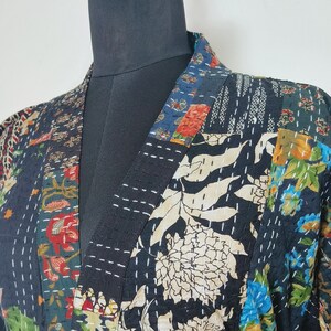 May include: A black quilted robe with a floral print and a tie belt. The robe is made of a patchwork of different fabrics and has a V-neck.