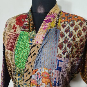 May include: A patchwork kimono-style robe with a variety of colourful fabric patterns. The robe features a mix of floral, geometric, and abstract designs in shades of red, green, blue, and yellow. The robe is tied at the waist with a matching belt.