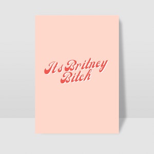 以下が含まれることがあります： ピンクの背景に、赤い筆記体で「It's Britney, Bitch」というテキストが書かれています。