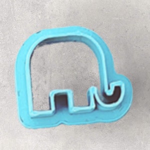May include: A light blue elephant-shaped cookie cutter. The cutter is made of plastic and has a simple, rounded design. The elephant's trunk and legs are clearly defined, making it easy to create detailed cookies.