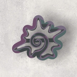 May include: A purple and teal seashell-shaped cookie cutter. The cutter features a swirling spiral design in the center and a wavy outline. The cookie cutter is made of metal and is likely used for baking.