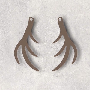 May include: Two brown antler-shaped ornaments with a small hole at the top for hanging. The antlers have multiple tines and are set against a light gray background.