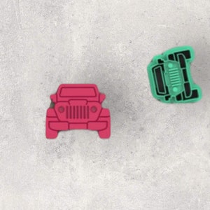 May include: Two toy jeep cookie cutters, one is pink and the other is green.