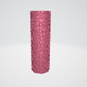 May include: A cylindrical, pink tumbler covered in a repeating pattern of hearts. The hearts are embossed on the surface, creating a textured effect. The tumbler is standing upright against a plain white background.