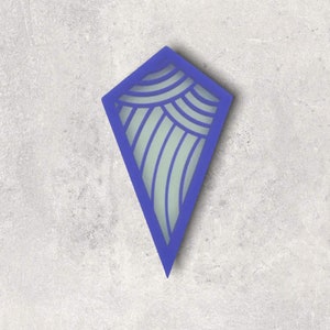 May include: A blue kite-shaped wall decor with a light green interior. The interior features a design of curved lines and semi-circles. The object is set against a gray, textured background.