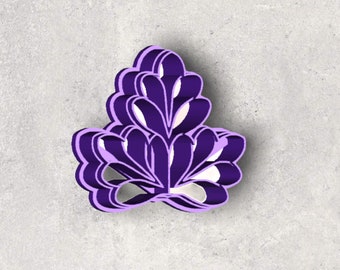 Può includere: Un oggetto a forma di fiore viola a strati con accenti bianchi. L'oggetto ha un aspetto tridimensionale, con più strati che creano profondità. Il design è simmetrico e si trova su una superficie grigio chiaro.