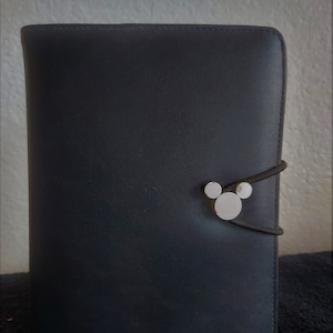 May include: A black leather bound journal with a silver Mickey Mouse head clasp.