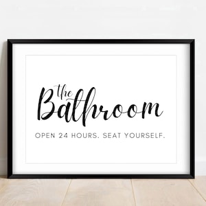 May include: Black and white framed print with the text "The Bathroom" in a cursive font. The text "Open 24 hours. Seat yourself." is printed below the main text.