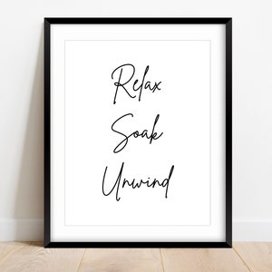 Può includere: Stampa incorniciata in bianco e nero con le parole "Relax Soak Unwind" in un font scritto a mano.