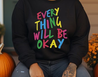Op de afbeelding: Een zwart sweatshirt met de tekst "EVERYTHING WILL BE OKAY" in kleurrijke letters. De letters zijn in een speelse, handgeschreven stijl.