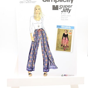 May include: A Simplicity S9595 Super Jiffy sewing pattern envelope featuring an illustration of a person wearing a white long-sleeve top and wide-leg pants with a blue, orange, and purple geometric pattern, including a smaller inset image of pattern 5082.