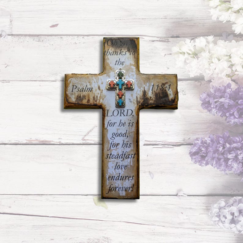 May include: A rustic wooden cross with a white background and a colorful mosaic design. The cross features the text "Psalm 118-1" and the words "Oh, give thanks to the LORD, for he is good, for his steadfast love endures forever!"
