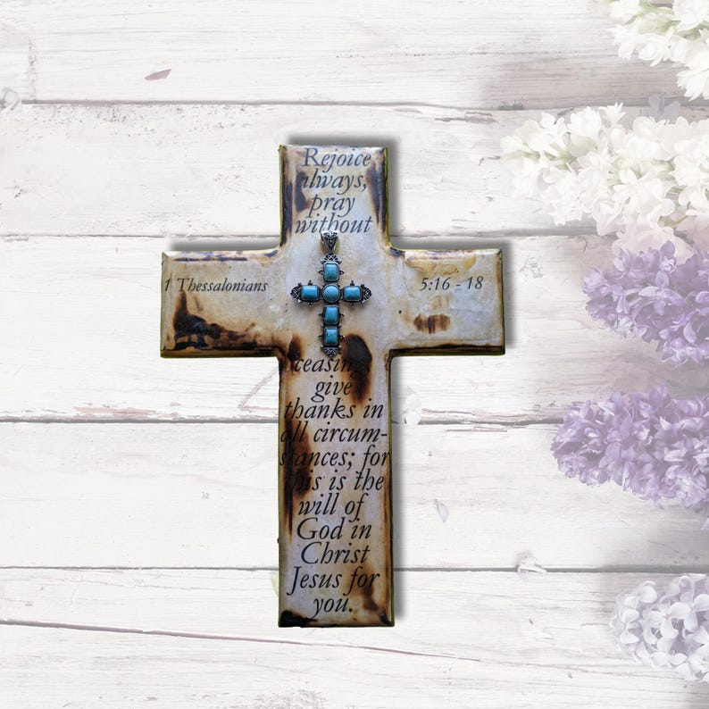 May include: A white wooden cross with a turquoise stone embellishment and the scripture "1 Thessalonians 5:16-18 Rejoice always, pray without ceasing give thanks in all circumstances; for this is the will of God in Christ Jesus for you."