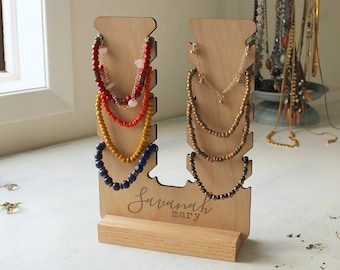 May include: Wooden jewelry stand with multiple tiers for displaying necklaces and bracelets. The stand is personalized with the name "Savannah mary".