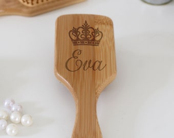 Puede incluir: Un cepillo para el cabello de madera con una corona y el nombre "Eva" grabado.