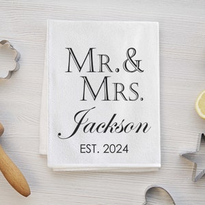 May include: White kitchen towel with black text that reads "Mr. & Mrs. Jackson Est. 2024".