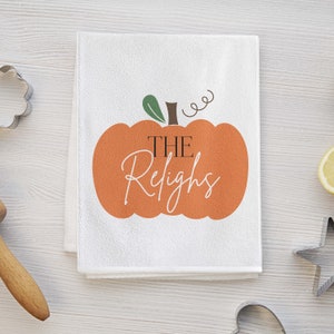 May include: White kitchen towel with an orange pumpkin design. The pumpkin has the text "THE Relights" inside.