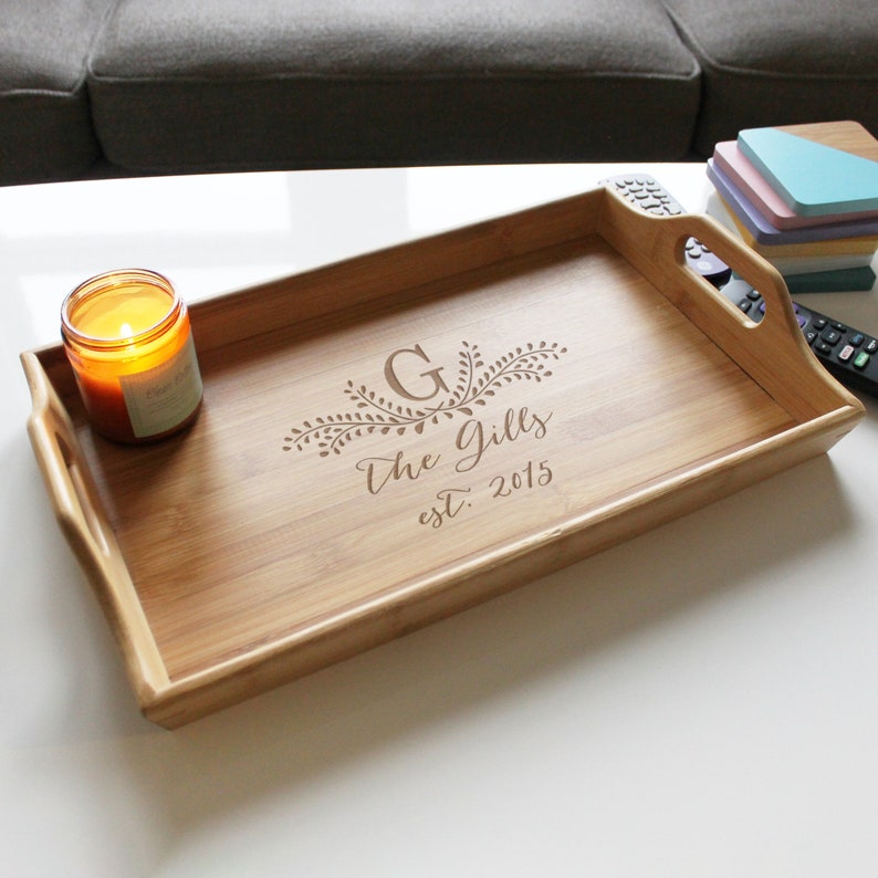 May include: A natural bamboo serving tray with a personalized engraved design. The design features a floral motif with the letter "G" and the text "The Gills est. 2015".