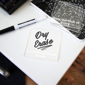 May include: A white dry erase coaster with black text that reads "Dry Erase" and "From the desk of Avery".