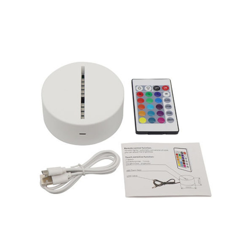 May include: A white round LED light base with a touch-sensitive control panel and a remote control. The remote control has 16 different color options and a brightness control. The light base is connected to a USB cable.