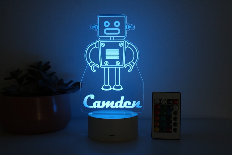 May include: A blue light-up robot nightlight with the name Camden on the base. The light has a remote control with multiple color options.