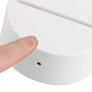 May include: White round base with a thin, white light strip on top. The base has a small, round power button on the side.