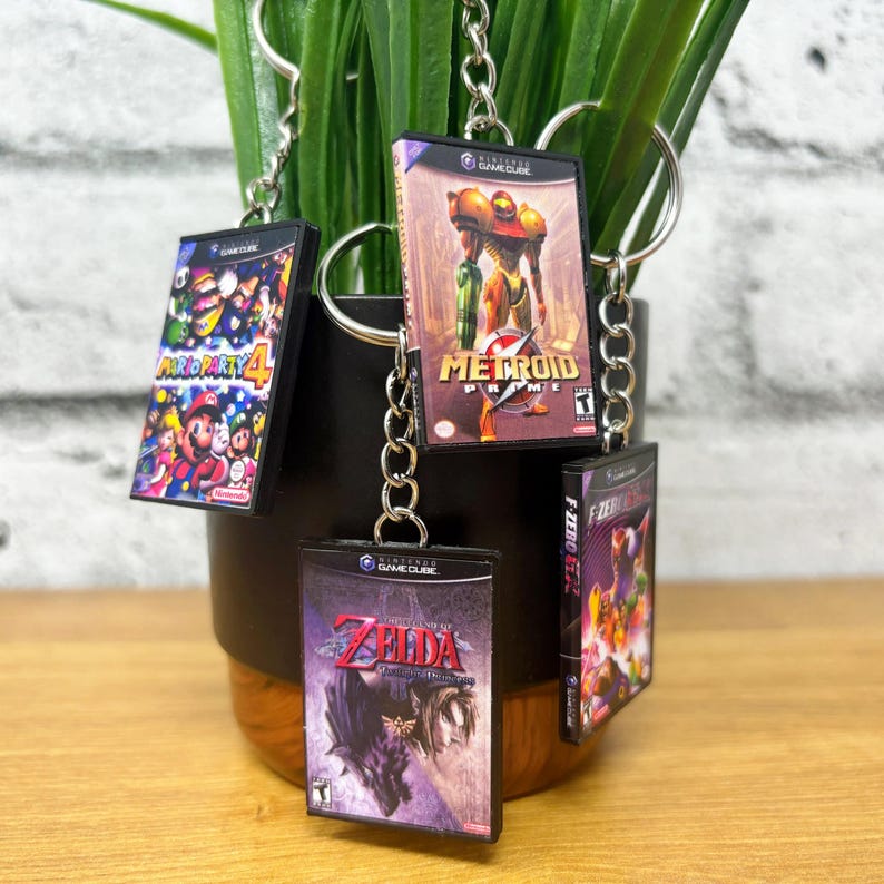 May include: Four miniature GameCube game cases attached to keychains. The cases feature the games "Mario Party 4", "Metroid Prime", "The Legend of Zelda: Twilight Princess", and "F-Zero GX".