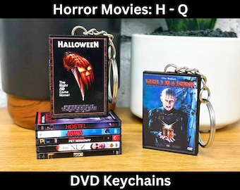 May include: DVD keychains featuring horror movie covers, including "Halloween" and "Hellraiser." The "Halloween" keychain shows a pumpkin with a knife. Other keychains include "Hostel," "Jaws," and "Pet Sematary." The text "Horror Movies: H - Q" and "DVD Keychains" are visible.