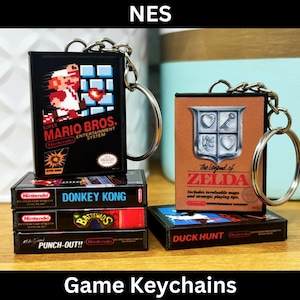 Puede incluir: Un conjunto de cinco llaveros de juegos de NES, que incluyen Super Mario Bros., Donkey Kong, Battletoads, Punch-Out!! y Duck Hunt. Los llaveros son negros con gráficos y texto coloridos.