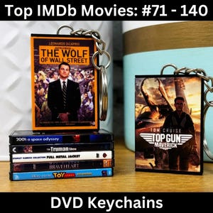 May include: A set of six DVD keychain keychains featuring popular films. The keychains are black with silver key rings. The films featured are "2001: A Space Odyssey", "The Truman Show", "Full Metal Jacket", "Braveheart", "Toy Story", and "Top Gun: Maverick".