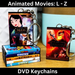 May include: A set of DVD keychain charms featuring popular animated movies, including Mulan, The Lion King, Toy Story, Monsters Inc., Batman, and Shrek 2. The charms are attached to silver keychains.