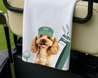 Puede incluir: Toalla de golf blanca con un perro de dibujos animados que lleva una visera verde con el nombre "Ollie". La toalla también tiene una pelota de golf y un gráfico de bolsa de palos de golf. La toalla está colgada en un carrito de golf.