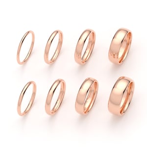 May include: Eight rose gold rings arranged in two rows of four, showcasing a gradient of increasing band widths from left to right. Each ring features a smooth, polished, rounded surface with a consistent metallic finish and a circular shape.