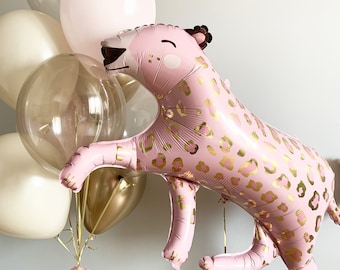 May include: A pink and gold leopard print balloon animal with a cute face. The balloon is surrounded by a cluster of other balloons in various shades of pink and beige.