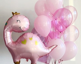 May include: A pink dinosaur shaped balloon with a gold crown and hearts on its body. The balloon is surrounded by a bunch of pink and clear balloons.