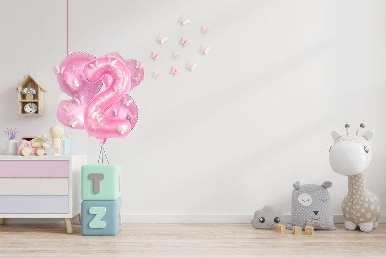 May include: Pink number two balloons with butterfly accents, a set of alphabet blocks spelling "T" and "Z", and a white giraffe stuffed animal with brown spots.