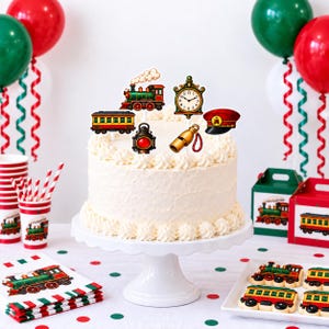 May include: A white frosted cake topped with train-themed decorations including a steam locomotive, a passenger car, a vintage clock, a red lantern, a gold whistle, and a red conductor hat, all arranged on a white pedestal cake stand.