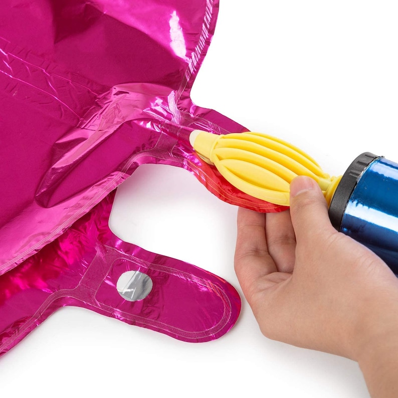 May include: A hand inflating a pink foil balloon with a yellow balloon pump. The balloon has a self-sealing valve.