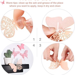 May include: Instructions on how to use 3D butterfly wall decor. The image shows a hand holding a butterfly and folding the wings to create a 3D effect. The image also shows a hand applying adhesive to the back of the butterfly and then attaching it to a wall.