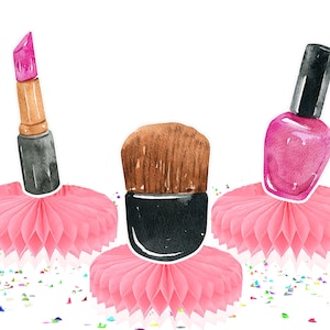 May include: Three pink honeycomb tissue paper decorations with a lipstick, makeup brush, and nail polish on top. The lipstick is pink and brown, the makeup brush is brown and black, and the nail polish is pink and black.