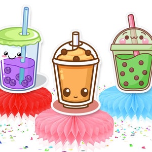 May include: Three cute cartoon bubble tea cups with smiling faces and different colored drinks. Each cup is on a colorful tissue paper pom-pom.