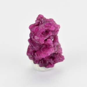 May include: A cluster of pink ruby crystals, a vibrant and colorful gemstone.