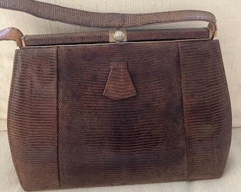 Peut inclure: Un sac à main marron vintage avec un motif texturé semblable à celui d'un reptile. Le sac est doté d'une poignée supérieure, d'une forme rectangulaire et d'une fermeture à fermoir. Ses dimensions sont d'environ 25 cm de large, 20 cm de haut et 10 cm de profondeur.