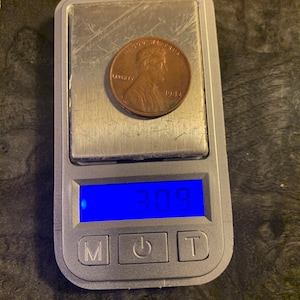 Puede incluir: Un centavo de cobre de 1932 en una báscula digital, que muestra un peso de 3,09 gramos.