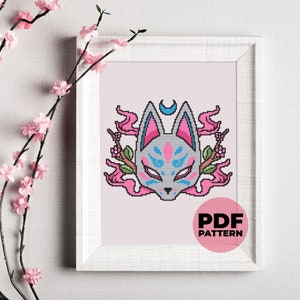 Puede incluir: Un patrón de punto de cruz con una máscara de zorro gris con detalles azules y rosas. La máscara está rodeada de llamas rosas y una luna creciente. El texto "PDF PATTERN" está impreso debajo de la imagen.