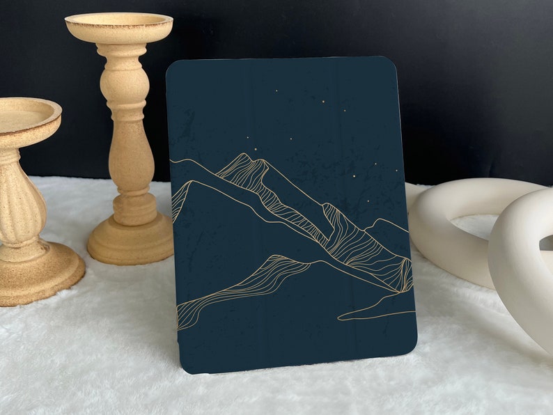 May include: A dark blue card with a gold outline of mountains and stars. The card is on a white surface.