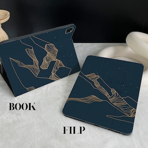 May include: Two dark blue phone cases with a gold line design. The design is of a mountain range. The text "BOOK" and "FILP" are printed on the white surface below the cases.