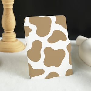 May include: A white and brown patterned phone case with a cow print design.